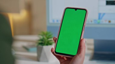 İş yerindeki yaratıcı ajansta el ele tutuşan akıllı telefon. Tanımlanamayan kadın yönetici yeşil ekran cep telefonundan SMS mesajı okuyor. Kadın patron krom anahtarlı cep telefonuna bakıyor.