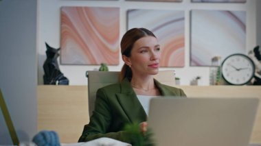 Gülümseyen patron latte fincanını gevşetiyor dizüstü bilgisayarla iş yerinde yakın çekim yapıyor. Sakin yönetici iş kadını kahve içiyor rahat rahat koltukta tek başına. Rahat kadın CEO, modern ofis odasında tatilin tadını çıkarıyor. 