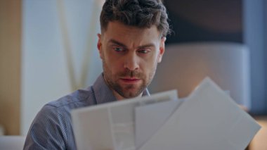 Kaşlarını çatan tasarımcı suratı modern çalışma alanındaki çizimleri inceliyor. Yaratıcı ajanstaki çizimleri karşılaştırmak için ciddi bir analizci. Tıraşsız, odaklanmış ve dolapta konsantre olmuş bir adam.