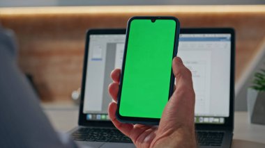 Ofiste cep telefonunun maketini tutan adam elleri. Tanımlanamayan yaratıcı yeşil ekrandaki haberleri kontrol ediyor. Chromakey uygulaması kullanan bilinmeyen tasarımcı. Sanatçı video çağrısı 