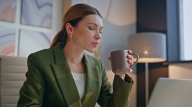 Rahat iş kadını, modern ofis masasında oturarak kahve molasının tadını çıkarıyor. Sakin kadın yönetici şirket işyerinde dizüstü bilgisayar ararken içki içiyor. Bilgisayarda çalışan çekici bir bayan. 