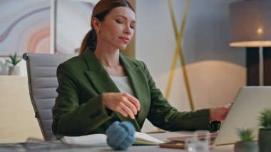 Sakin bir iş kadını, modern ofis masasında otururken kahve molasından zevk alır. Dizüstü bilgisayarın çalışma yerinde içki içen mutlu, rahat kadın yönetici. Çekici dinlenen bayan topu pencereye götürüyor.