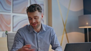 Aşırı neşeli mimar ofiste sanal konferansa gülüyor. Gülümseyen adam dizüstü bilgisayarla ortak video görüşmesi yapıyor. Projeyi ilham kaynağı ile sunan neşeli profesyonel holding sunucuları