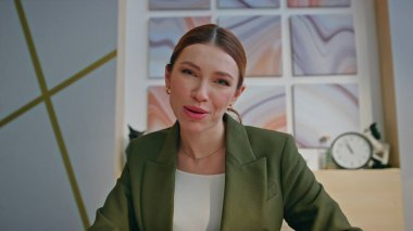 Ofisteki video görüşmesinde konuşan mutlu online öğretmen POV görünümlü. Çekici, gülümseyen kadın sanal sohbet yoluyla müşteriye danışıyor. Neşeli pozitif bayan patron iş yerinde uzaktan konferans veriyor.