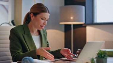 Ofiste sanal konferans konuşması yapan ilham verici bir kadın. Gülümseyen mimar ortak konuşuyor. Bilgisayarı ara bağla. Neşeli, yaratıcı, notlar alan, inceleme projesi sunucuları