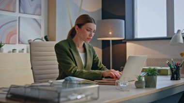 Ofiste klavye yazan düşünceli bayan çalışan yakın plan bilgisayarı. Rahat iş kadını notlar yazıyor ve modern masada yoğunlaşıyor. Sakin kadın yönetici masadaki iş yerine dizüstü bilgisayar bakıyor