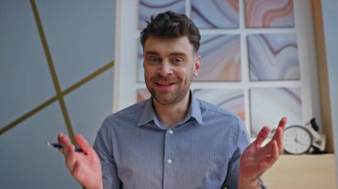 Ofisteki video konferansında konuşan neşeli online öğretmen POV görünümlü. Çekici gülümseyen adam sanal sohbet yoluyla müşteriye danışıyor. Mutlu pozitif patron konuşuyor. İş yerinde uzaktan konferans jesti.