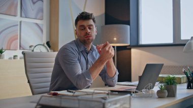 Yaratıcı kabinede evrakları kontrol etmekten yorulmuş bir uzman. Düşünceli tasarımcı dizüstü bilgisayarın iş yerine attığı çizimleri inceliyor. Düşünceli, yorgun, tatminsiz, yalnız görünen bir çözüm. 