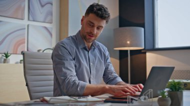 Modern ajans bürosunda dizüstü bilgisayarı daktilo eden programcıdan esinlendim. Memnuniyetle gülümseyen adam referansları inceliyor. Ofisin içinde tek başına başarının tadını çıkarıyor. Yaratıcı projeye dahil olan mutlu uzman adam.