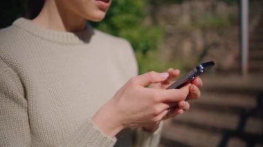 Güneş ışığı parkında akıllı telefon yazan kadın elleri yakın plan. Tanımlanamayan bir kadın, Summer City 'de cep telefonuna mesaj atıyor. Kimliği belirsiz bir kız sıcak bahçede cep telefonuna mesaj atıyor.