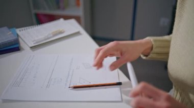 Öğretmen elleri yakın çekimde iz bırakıyor. Tanımlanamayan eğitimci, hafif bir iç mekanda kalem kullanarak ev işlerini kontrol ediyor. Okul sınavlarında ödevlerini düzelten kimliği belirsiz genç bir kadın.
