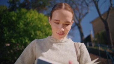 Yeşil ağaçların önünde duran mutlu, kendine güvenen kadın kitabı çeviriyor doğa yakın. Şık romantik bayan öğretmen, Sunshine City caddesinde dizüstü bilgisayarını tek başına tutuyor. İş mesleği kavramı 