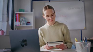 Zeki bir kadın, sınıfta bilgisayar ekranına bakarak online ders veriyor. Gözlüklü gülümseyen öğretmen kabine bilgisayarına uzaktan bakıyor. Sanal sohbet yapan genç profesör.