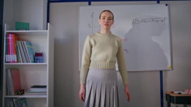 Konuşan öğretmen okulda matematiği açıklıyor. Odaklanmış kadın eğitimci sınıfta denklem çözmeyi öğretiyor. Genç profesör sadece kabinede çevrimiçi kayıt dersini işaret ediyor.