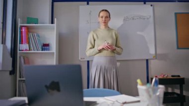 Genç öğretmen ayakta duran matematiği açıklıyor. Dost canlısı bir kadın sınıfta online ders kaydı yapıyor. Okulda uzaktan çalışan gülümseyen bayan öğretmen. Uzaklık eğitimi kavramı