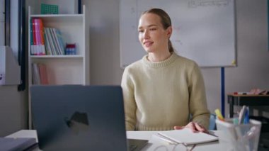 Genç öğretmenler online derslere dizüstü bilgisayarla başlayan öğrencileri sınıfa yakın oturarak selamlıyor. Sosyal ağlarda eğitim kanalını yöneten zeki, güler yüzlü bir kadın. Bayan antrenman kursu. 