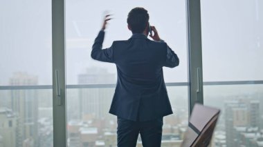 Öfkeli girişimci, şehir merkezinin arka planında el hareketi yaparak hayal kırıklığına uğrattı. Sinirli sakallı iş adamı, büyük pencerelerin önünde cep telefonu konuşmasında stres hissediyor. Duygusal patron.