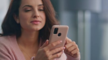 Modern mutfakta cep telefonu okuyan rahat bir kadın. Gülümseyen kaygısız bayan cep telefonuyla evde eğleniyor. Mutlu esmer kız hafta sonunu yalnız takılarak geçiriyor. İnsan yaşam tarzı 