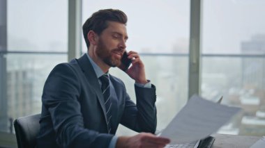 Yakın plan mutlu iş adamı cep telefonunu arıyor şehir merkezinde oturuyor. Kendine güveni tam bir yönetici. İş yerinde akıllı telefon aranıyor. Şık patron telefonda müşteriye danışıyor. 