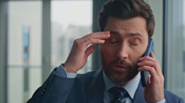 Umutsuz yönetici ofis penceresini kapatıyor. Telefon konuşmalarında kötü haber duyan üzgün işadamı cep telefonu iletişiminden sonra strese girdi. Yorgun işçi konuşmasını bitir.