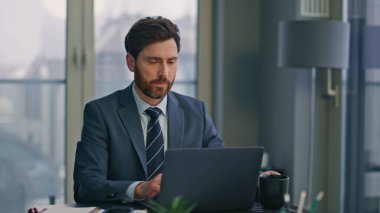 Ciddi bir iş adamı panoramik pencerelerde bilgisayarına mesaj atıyor. Modern ofis içinde çalışan odaklanmış sakallı bir adam kahve yudumluyor. Sakin zengin yönetmen masadaki iş e- postalarını okuyor 