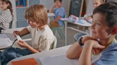 Yaramaz çocuklar yakın çekimde eğleniyor. Sınıfta oturan meraklı çocuk sınıf arkadaşının notlarını okuyor. İlkokul kabinesinde birbirleriyle iletişim kuran iki komik öğrenci. Sevimli öğrenciler.