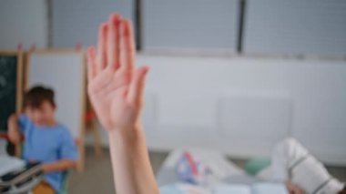 Küçük öğrenci, yakın çekimde el kaldırıyor. Sınıfta öğretmenini dinleyen tanınmamış bir çocuk soruya cevap veriyor. Okulun oditoryumunda bilinmeyen çocuk eğitimi. Küçük okul çocuğu sınıf öğreniyor.