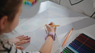 Sanat atölyesinde resim çizen küçük bir kız. Odaklanmış küçük sanatçı okul stüdyosunda zaman geçiriyor. Büyük masada kağıt yapan, elinde kalem tutan tanınmamış yetenekli bir çocuk. İlham konsepti