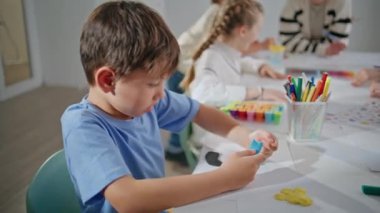 Okul masasında plastik oymacılık yapan ilham verici bir öğrenci. Düşünceli okul çocuğu kendini sanat dersinde yoğunlaşmış hissediyor. Küçük bir öğrenci oditoryumda resim yaratıyor. Küçük çocuk yaratıcılık süreci