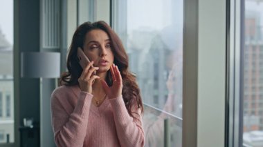 Endişeli kız kasvetli camlı şehirde cep telefonuyla konuşuyor. Gergin bayan akıllı telefonu arıyor ve evde hayal kırıklığına uğramış hissediyor. Kafası karışmış güzel bir kadın, kafaya dokunuyor. Dairede stresli bir model. 