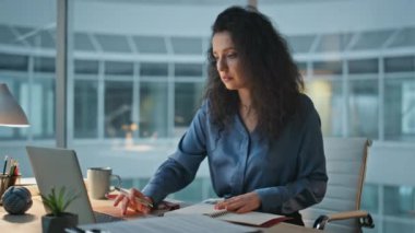 Akşamları masa başında çalışan odaklanmış bir kadın. Curly ofiste dizüstü bilgisayar kullanmakla meşgul. Profesyonel yönetici evrakları gözden geçiriyor. Esmer iş kadını geceleri işleri yönetiyor..