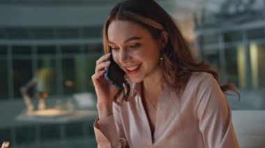Gülümseyen iş kadını cam gece ofisinde telefon görüşmesi yapıyor. Akıllı telefon görüşmesinde danışmanlık yapan neşeli profesyonel bir ortak. Mali uzman raporunu gözden geçirip iş görüşmeleri yapıyor