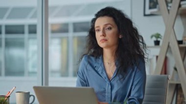 Upset executive thinking problem at agency desk. Closeup frustrated employee working at laptop planning project. Serious brunette businesswoman sit in evening office. Contemplative corporate worker