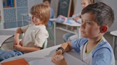 Sınıfta oturan sevimli öğrenciler yakın çekim yapıyor. Meraklı çocuklar dinleyip eğleniyorlar. İlkokul kabinesinde birbirleriyle iletişim kuran iki komik çocuk. Çocuk sınıf arkadaşına not veriyor.