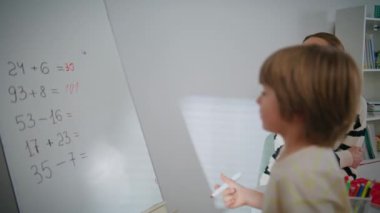 Genç öğretmen, çocuğa sınıfa yakın çekim için sesleniyor. Matematik öğretmeni dersi açıklıyor. Akıllı öğrenci oditoryumda keçeli kalemle yazı tahtası alıyor. Okulda okuyan çocuk 