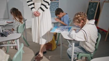 Küçük öğrencilerle birlikte sınıfa giren bilinmeyen bir öğretmen. Çalışkan öğrenciler ilkokulda birlikte ders kitabı yazıyorlar. Akıllı çocuklar ders sırasında cevapları deftere yazarlar. 