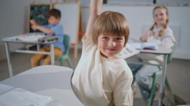 Mutlu çocuk derste el kaldırıyor. Gülümseyen öğrenci, sınıfın portresindeki soruyu cevaplıyor. Akıllı çocuk derslerden zevk alıyor. Küçük zeki öğrenci sınıfta öğreniyor.
