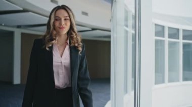 Mutlu iş kadını toplantı için ofis salonuna gidiyor. Yakın plan başarılı kadın cam kenarında şık bir takım elbiseyle yürüyor. Gülümseyen menajer koridorda profesyonel planlama yapıyor. Pozitif şirket lideri.