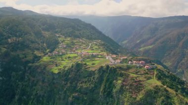 Yeşil yamaçlara kurulmuş rahat bir köy, sakin hava manzarasının etrafını sarmıştı. Bulutlu gökyüzünün altında sakin kırsal kesimlerdeki canlı dağ tepelerinde resimli evler. Güzel doğanın yerleşim yeri.