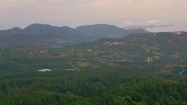 Gökyüzü manzaralı geniş yeşil dağlar ve küçük köylü vadiler. Doğanın sükunetini vurgulayan manzaralı bir yer. Bulutlu ufka uzanan alanlar ve ormanların panoramik manzarası.