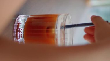 Modern restoranda samanla kokteyl karıştıran bir kadın. Yakın plan. Tanımlanamayan bir kız soğuk içecekten hoşlanır. Kafe masasında dikey olarak oturmaktan hoşlanır. Meçhul kadın, buzlu içecekle birlikte bardak getir..