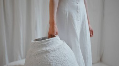 Sanatçının el ele tutuştuğu vazo yaratıcı stüdyoda yakın planda. Evdeki kadın dekoratör iç tasarım üzerinde çalışıyor. El yapımı kavanoz el yapımı sanat eserleri olan tanınmamış kız tasarımcı. Sanatçı kadın hobisi.