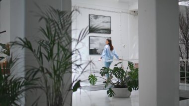 Duvarda resimlere bakan düşünceli bir kadın. Modern müzenin dikiz görüntüsünde sanat eserlerini izleyen odaklanmış bir ziyaretçi. Esmer kız sanat galerisinde hafta sonunun tadını çıkarıyor. İlham hobisi kavramı.