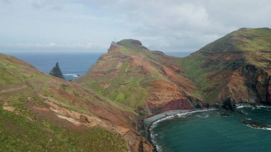 İnsansız hava aracı volkanik ada lagünü yaz günü. Uçurumların manzarası çok güzel. Sakin dalgalar köpüklü kayalık kıyıları yıkıyor. Güzel okyanus körfezi hava manzarası. Seyahat gezisi keşfi.