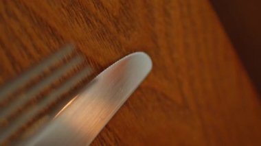 Çatal bıçağı modern kafeteryayı beyaz peçeteyle kapatmış. Ahşap masa restoranında duran zarif metal çatal bıçak seti ziyaretçilerin dikey çekimini bekliyor. Minimalist tasarımı olan şık kafe sofra takımı