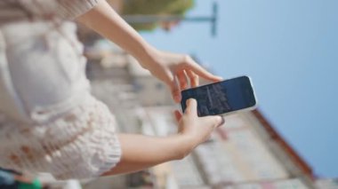 Turist, yaz tatilinde şehir mimarisinin güzel fotoğraflarını çekiyor. Akıllı telefon kullanan güzel bir blogcu. Güneş ışınları caddesinde tatil fotoğrafları çekiyor. Turizm konsepti 