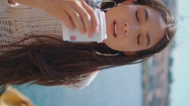 Deniz kenarında çay içen bir kız. Şehir turistleri, nehir kenarında dikey bir şekilde sabah içkisinin tadını çıkarıyorlar. Cappuccino yudumlayan güzel kadın. Seyahat kavramı 