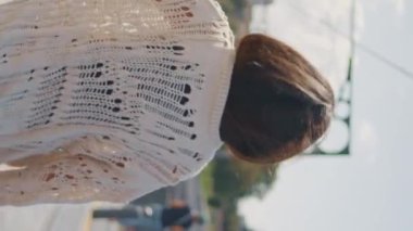 Gülen kadın, kamerayı köprü manzarasına çeviriyor. Kaygısız turist kadın yaz tatilinin tadını çıkarıyor. Yakın çekim dikey çekim. Esmer Latin kız, Güney Şehri 'nde poz veriyor..