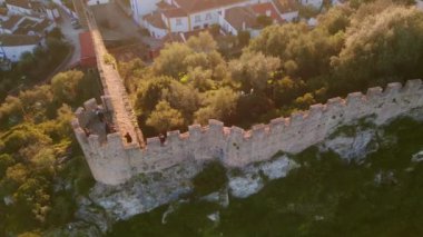 Ortaçağ kasabası boyunca uzanan antik kale duvarı yemyeşil hava manzarasını çevreledi. Tarihi mimari taş kale yapısı pitoresk şehir manzarası yaratır. Altın akşam ışığında eski bir şehir.