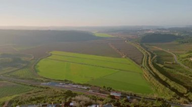 Gökyüzü manzaralı yeşil tarlalar ve güneşli kırlarda tarım arazileri. Drone tarımsal çevre ve gökyüzü ufkunun manzaralı manzarasını çekti. Canlı kırsal vadiye kurulmuş samimi küçük bir kasaba..